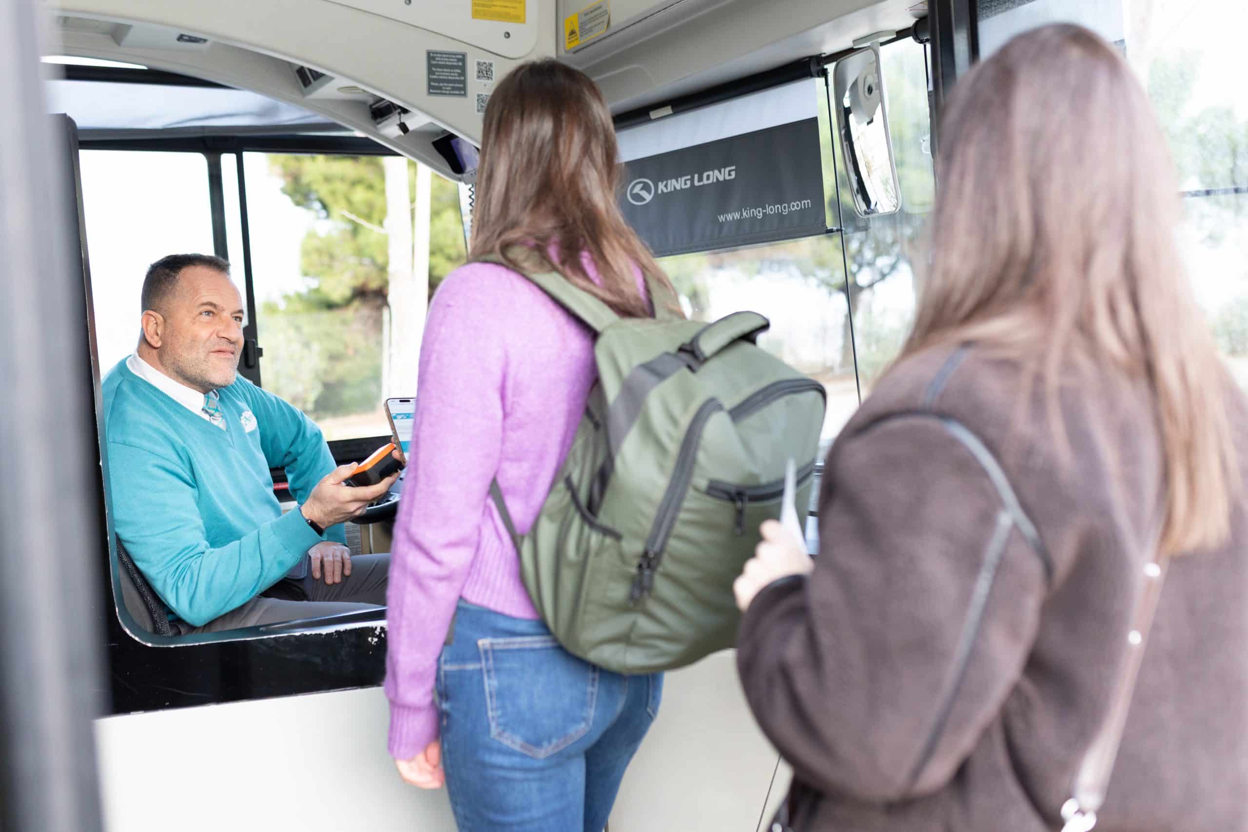 Conductor Aerobús vendiendo billete a dos pasajeras