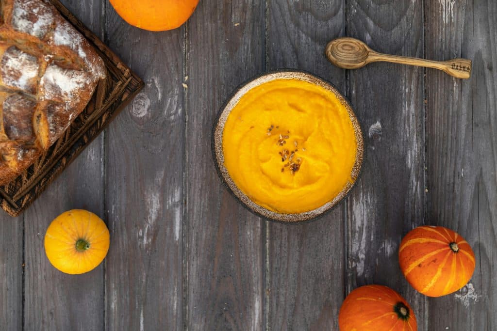 Plate of pumpkin cream surrounded by pumpkins