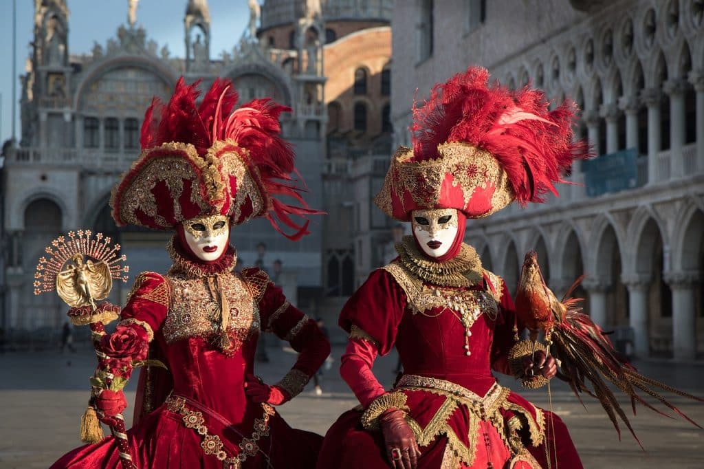 Two people in red Carnival costumes with Venetian masks