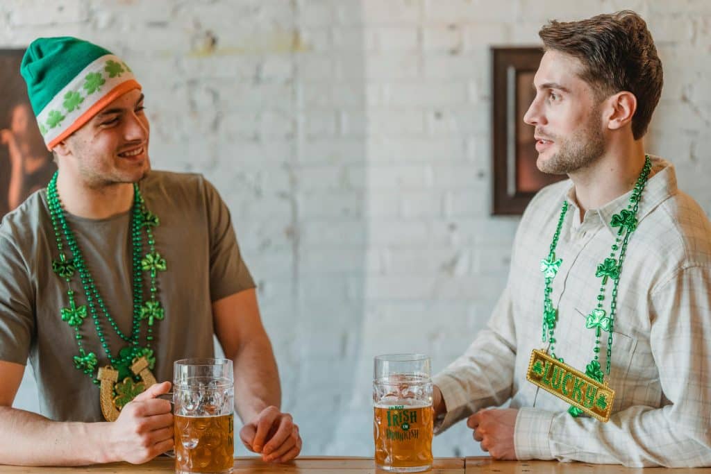 Two friends drinking beer in St. Patrick's Day themed attire