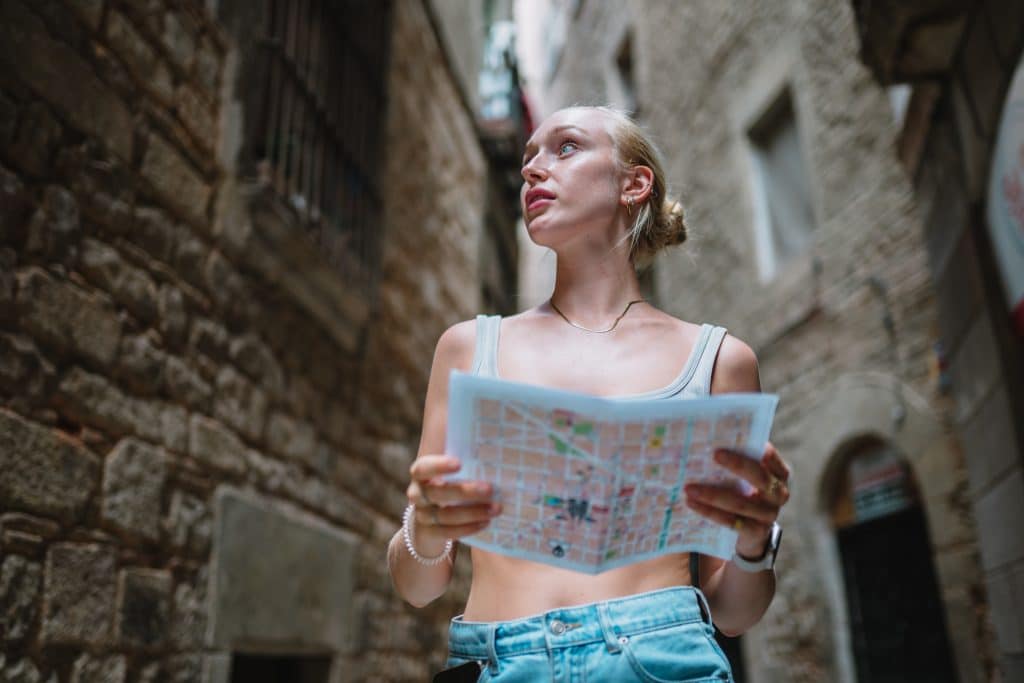 Chica turista en una calle de Barcelona con un mapa en la mano